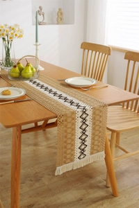Detail of bohemian woven table runner featuring black diamond patterns and white fringe