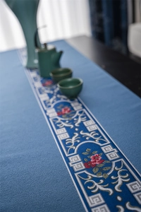 Close-up of blue table runner with traditional floral embroidery and vintage tassels