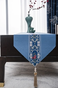 Close-up of blue jacquard table runner with traditional floral patterns and silk tassels