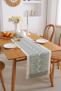 Close-up of forest reindeer jacquard table runner with handmade fringe tassels