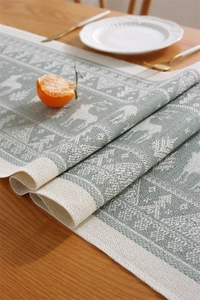 Close-up of jacquard table runner with elk and pine tree patterns and fringe details