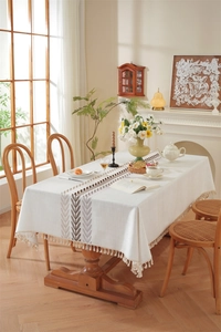 Detail of embroidered leaf pattern and fine fringe on cream linen rectangular tablecloth