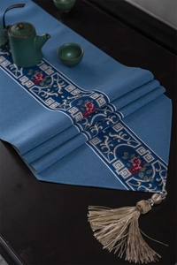 Detailed embroidery of Chinese style table runner with elegant tassels on a dark wood table