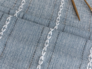 Macro shot of light blue jacquard tablecloth with white butterfly embroidery and cutouts