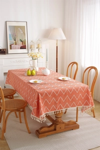 Detailed view of orange bohemian tablecloth with white chevron pattern and tassel edges