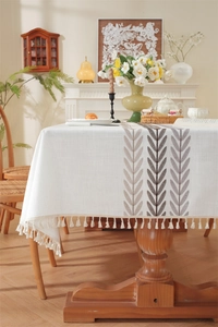 Detailed close-up of embroidered floral pattern and fringe tassels on linen tablecloth