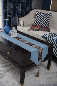 Detail of blue table runner featuring brown tassel and traditional Chinese pattern