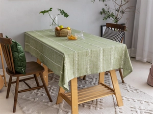 Detail of green table runner with white geometric embroidery on wooden dining table