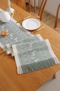 Close-up of Nordic reindeer jacquard table runner with handmade tassels on wooden table