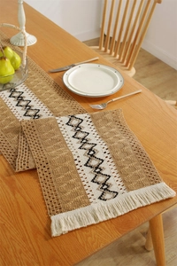 Detail of woven table runner featuring geometric black and white embroidery and soft tassels