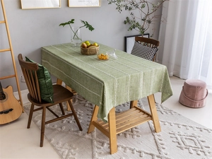 Close-up of green jacquard tablecloth with white vertical stripes and chain patterns