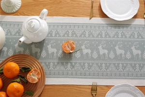 Detail of Christmas table runner with reindeer and pine tree jacquard patterns on wood