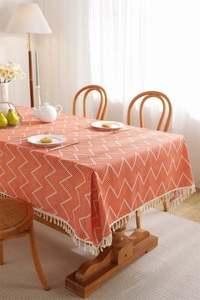 Close-up of orange geometric weave tablecloth with decorative white fringe trim