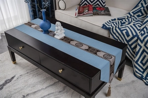 Detailed embroidery and brown tassel on a light blue traditional Chinese table runner