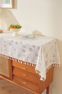 Detailed view of white lace table runner featuring snowflake patterns and fringe tassels