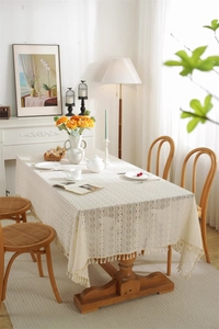Macro view of beige lace tablecloth featuring geometric crochet patterns and fringe edges