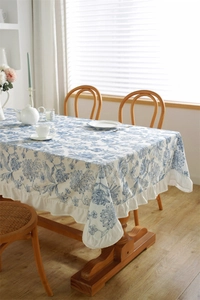 Close-up of blue floral embroidery on white cotton tablecloth with ruffled edges