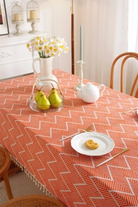 Detail of orange geometric pattern tablecloth featuring decorative white edge tassels
