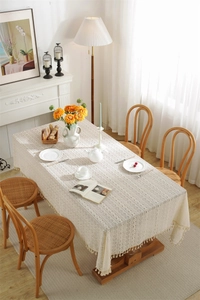 Detailed view of beige lace tablecloth featuring geometric hollow patterns and fringe tassels
