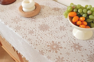 Detailed close-up of cream table runner with brown snowflake patterns and tassel edges