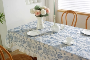 Detail of blue floral cotton tablecloth with elegant white ruffled edges in home setting