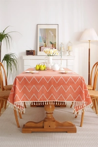 Detail of bohemian orange rectangular tablecloth with white geometric waves and tassels