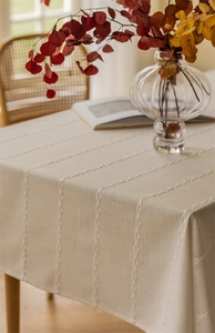 Detailed view of beige jacquard tablecloth with braided texture on a wooden dining table