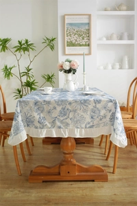 Detail of blue floral cotton tablecloth featuring elegant white ruffled lace edges
