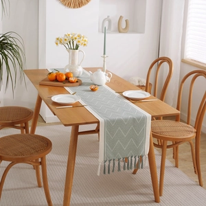 Geometric jacquard table runner with tassels on a wooden dining table in a cozy home setting