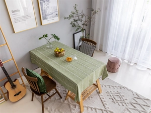 Detailed top-down view of green striped polyester jacquard tablecloth on a wooden dining table