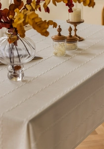 Macro view of textured geometric chain embroidery on beige rectangular tablecloth