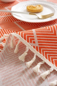 Detailed shot of orange geometric pattern tablecloth with handmade cotton fringe tassels