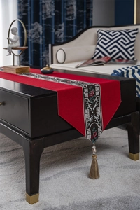 Detailed view of red Chinese style table runner with embroidery and gold tassel