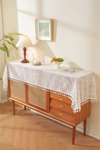 Close-up of French lace table runner with tropical leaf patterns and fringe detail