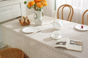 Macro detail of beige lace tablecloth with geometric hollow patterns and fringe edges