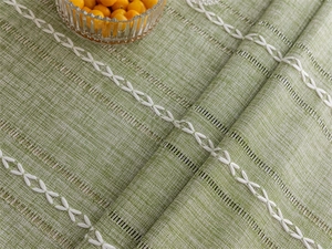 Macro shot of green geometric jacquard tablecloth with white diamond embroidery and cutouts