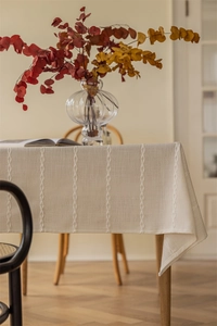Detailed close-up showing the braided white embroidery and linen texture of table runner