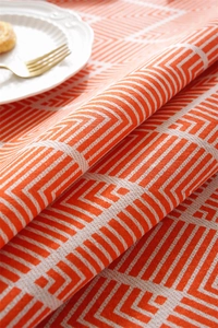 Close-up of orange geometric bohemian tablecloth with white maze pattern and table setting