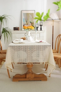 Detailed macro of beige lace tablecloth featuring geometric hollow knit and fringe edge
