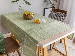 Close-up of green jacquard tablecloth with white geometric diamond embroidery detail