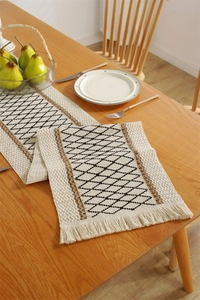 Close-up of cotton linen table runner with black diamond pattern and fringe detail