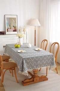 Detail of grey geometric pattern tablecloth with elegant off-white tassel edges
