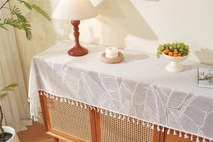 Close-up of white lace table runner with palm leaf pattern and delicate tassel edge