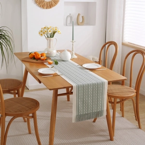 Modern jacquard table runner with geometric patterns and tassels on a wooden dining table