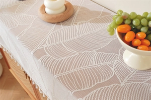 Detail of beige lace table runner with feather leaf patterns and fringe edges