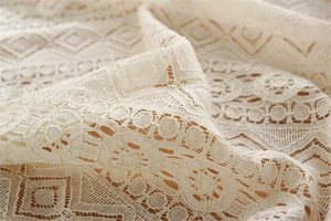 Detailed macro view of beige lace tablecloth with geometric diamond embroidery and tassels
