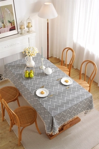 Detail of bohemian rectangular tablecloth featuring herringbone texture and beige tassels