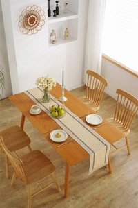 Close-up of yellow diamond pattern linen table runner with delicate fringe on wood table
