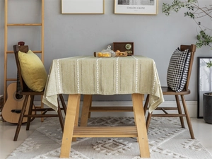 Detail of light green tablecloth featuring white braided embroidery and fabric texture