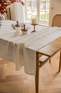 Detail of white jacquard table cloth with braided line texture on a wooden table